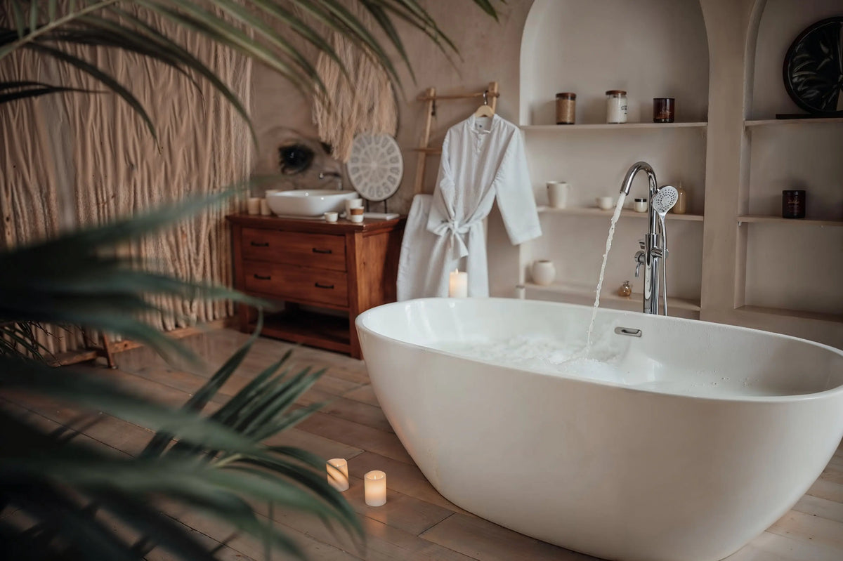 Modern white freestanding bathtub with a chrome faucet in a luxury spa-style bathroom.