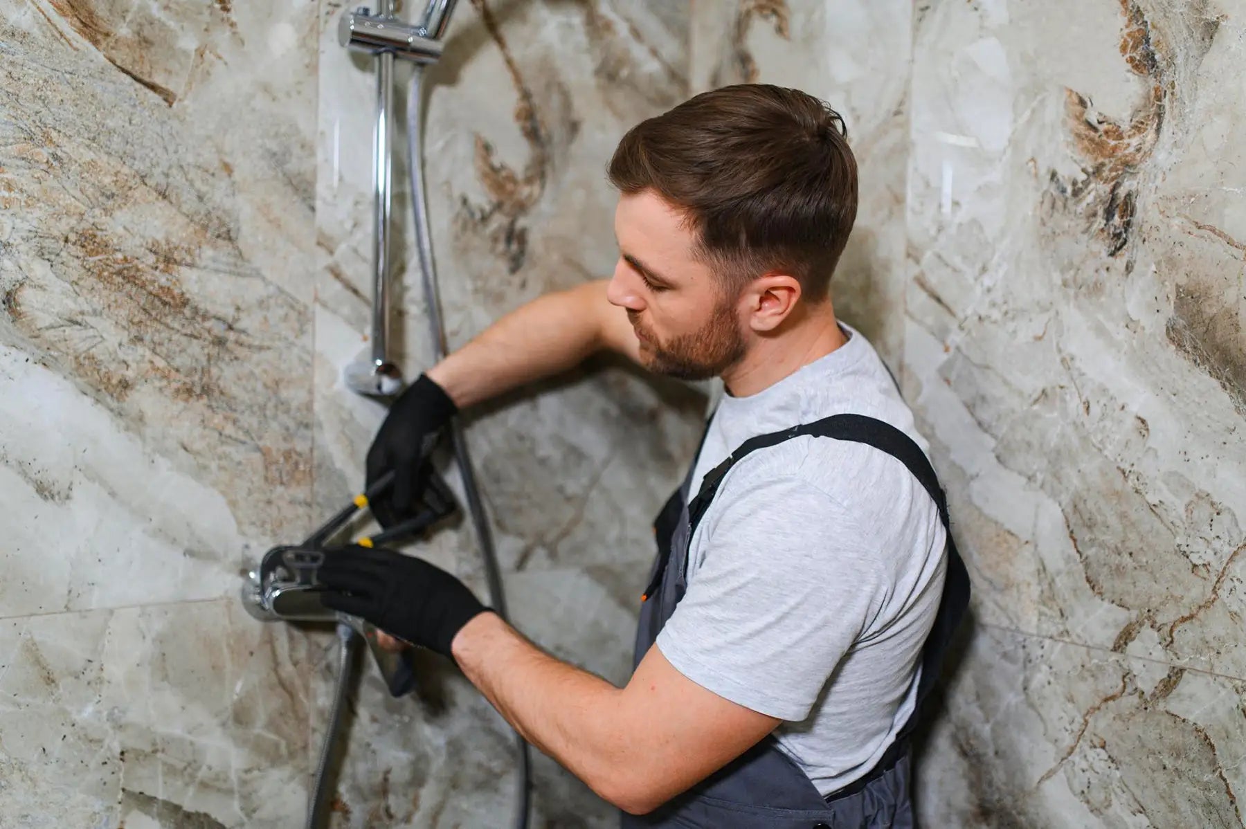 Professional installing shower hardware in bathroom.