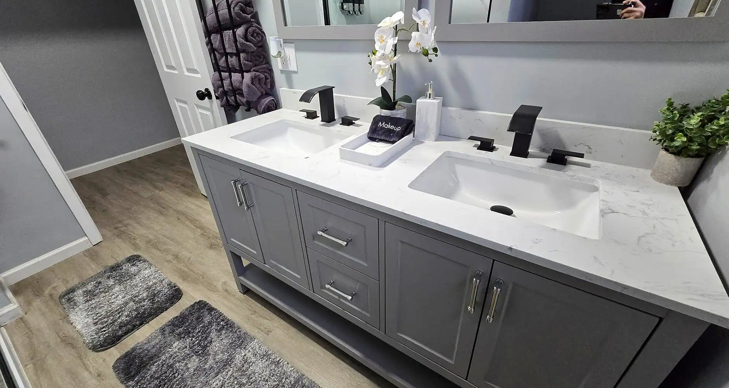 Gray double-sink bathroom vanity with a white marble-look countertop, black faucets, silver hardware, and a large wall mirror.
