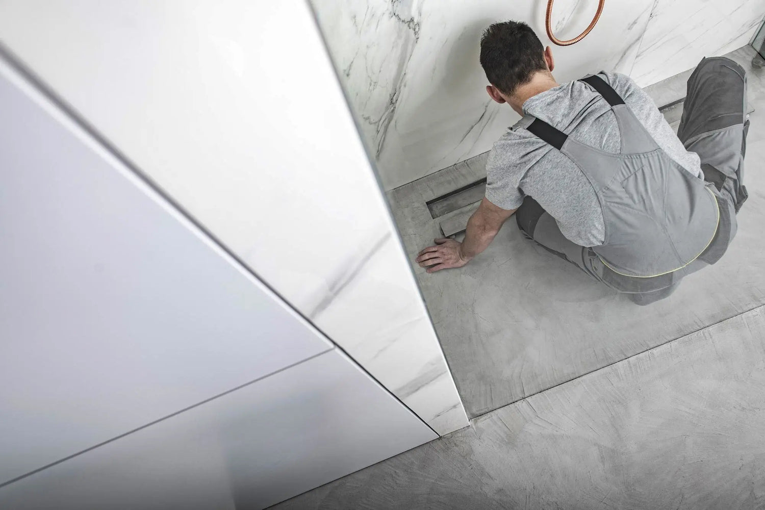 Installer fitting a shower base pan inside a tiled shower enclosure.