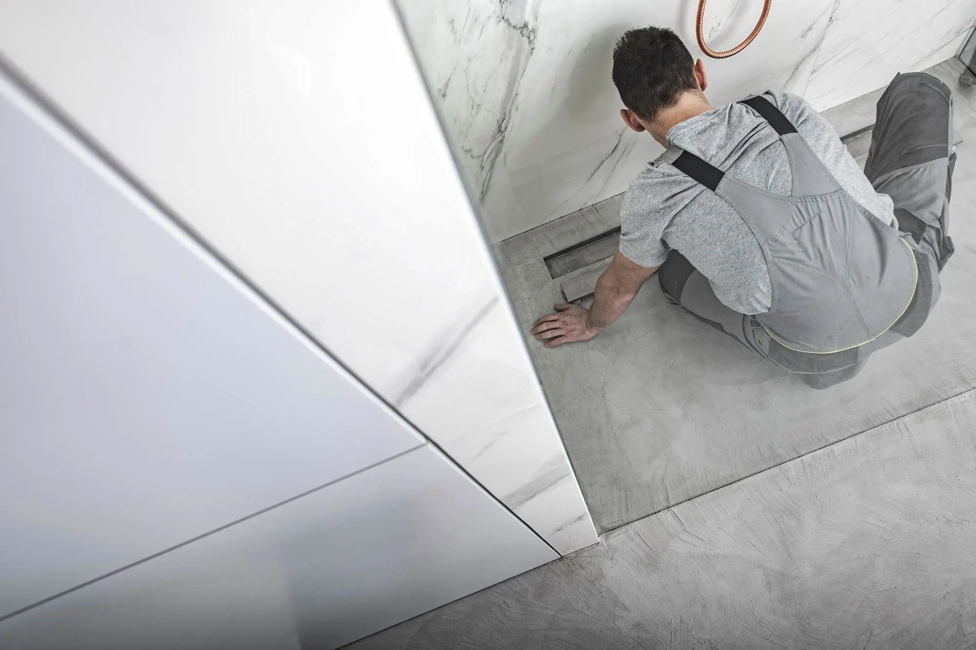 Installer fitting a shower base pan inside a tiled shower enclosure.