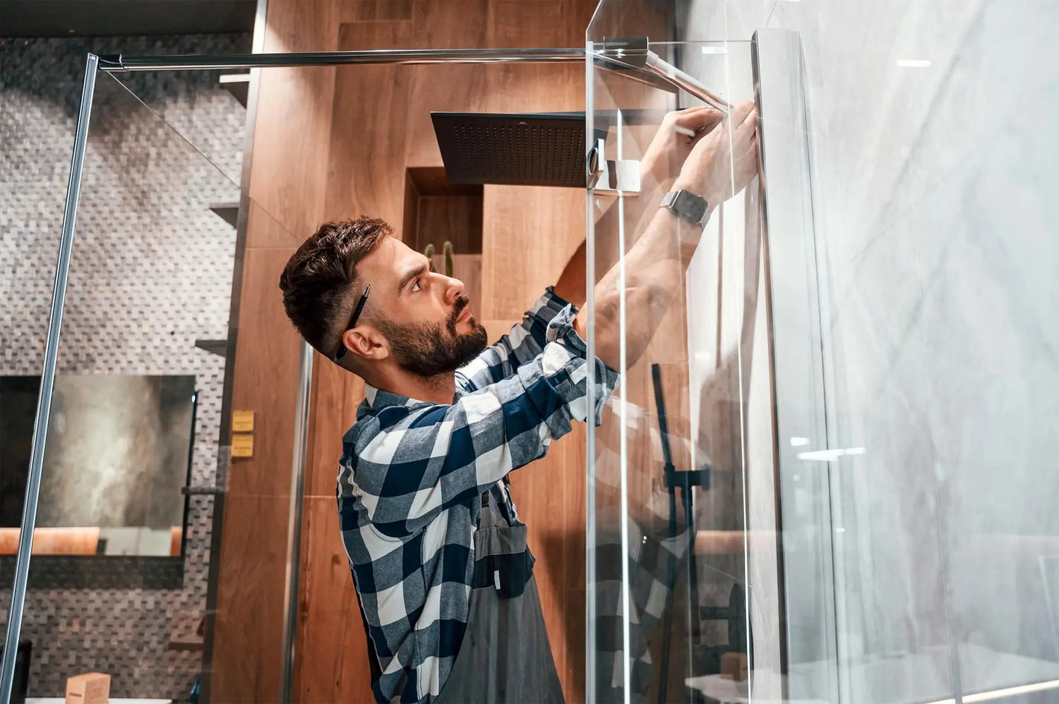 Installer securing a frameless glass shower enclosure in a modern bathroom.