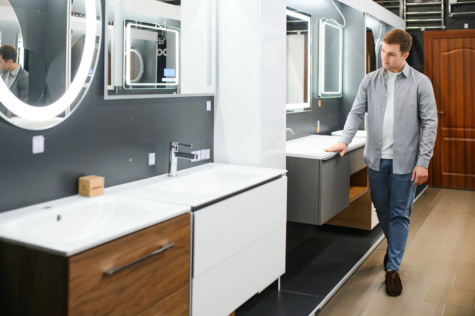 Man browsing modern bathroom vanities in a Dreamwerks showroom.