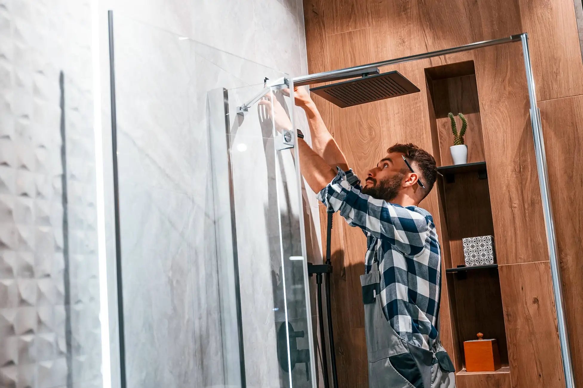 Installer adjusting a glass shower door in a modern bathroom.