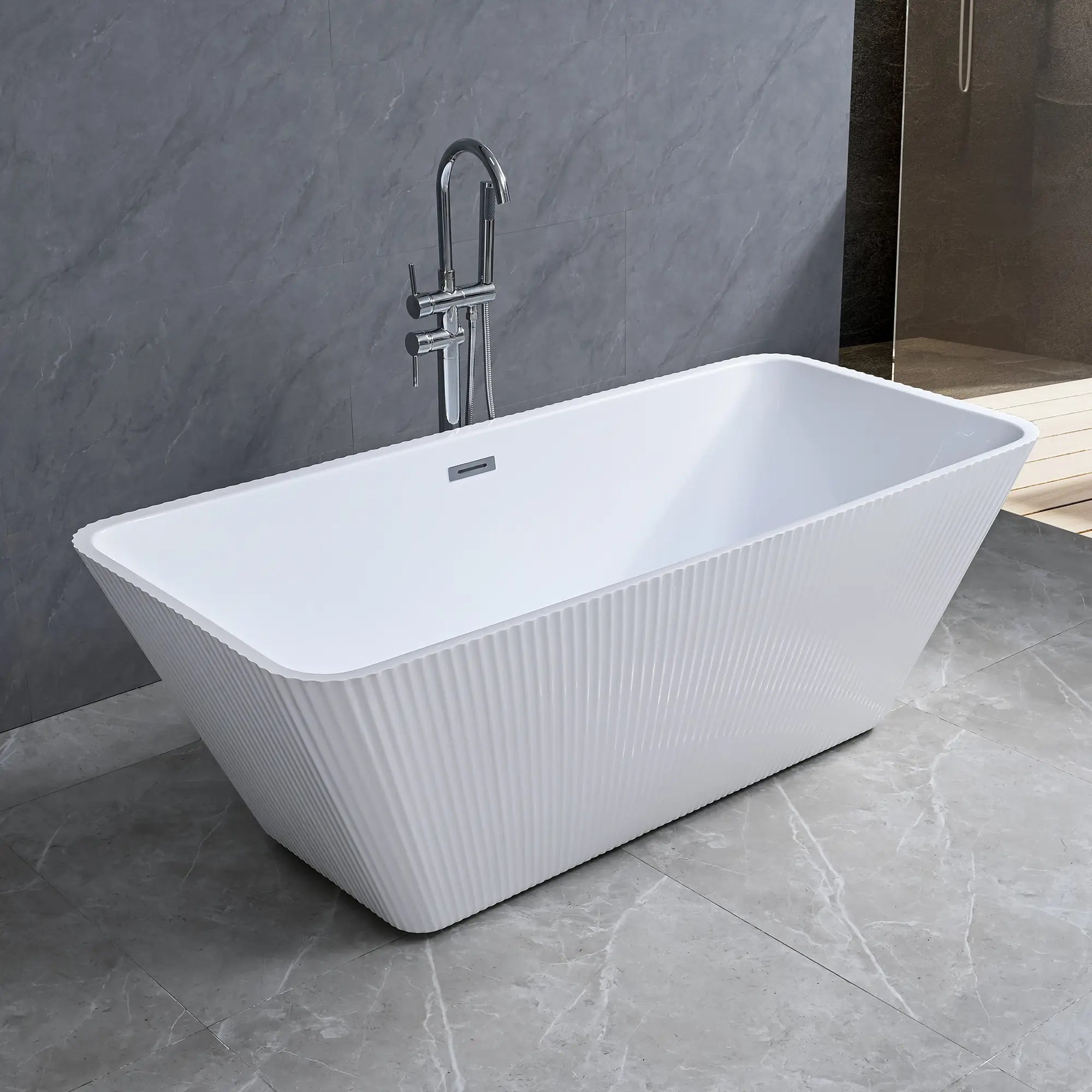 Dreamwerks white fluted freestanding bathtub in a modern bathroom with gray tiles and a shower in the background.