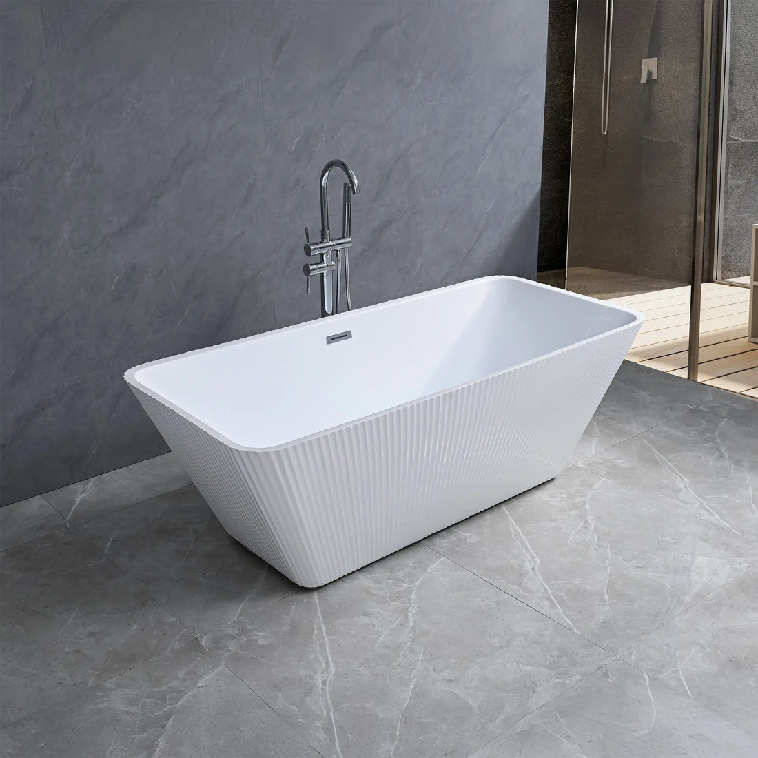 Dreamwerks white fluted freestanding bathtub in a modern bathroom with gray tiles and a shower area.