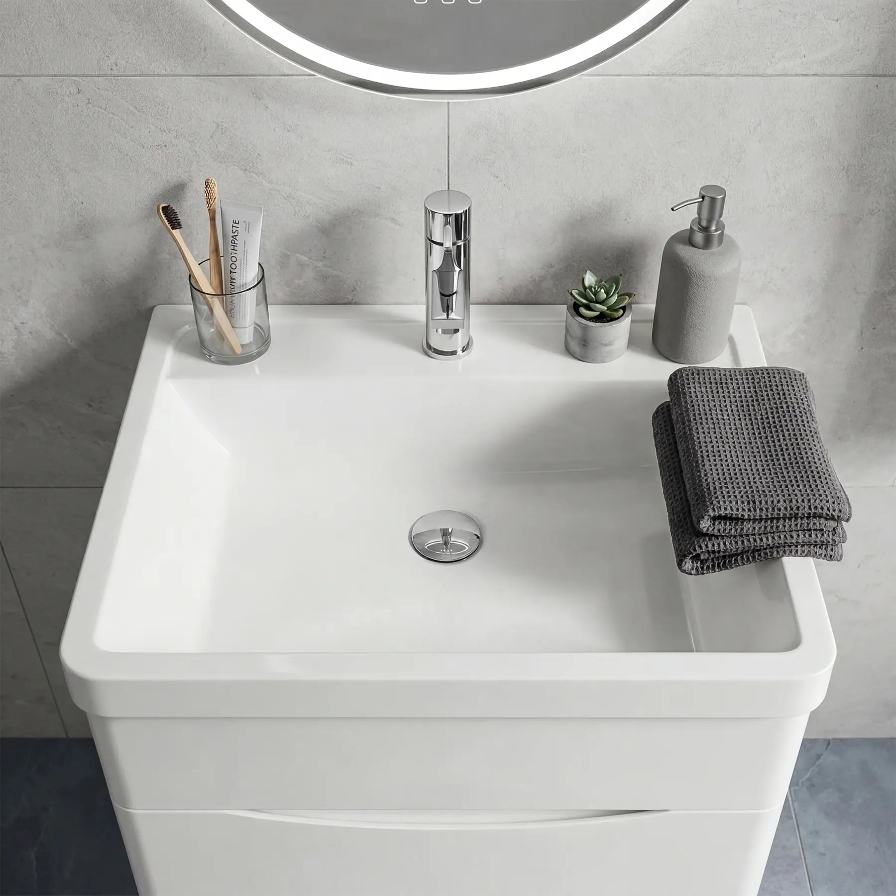 Bathroom vanity with sink, mirror, and toiletries on a gray tiled wall background