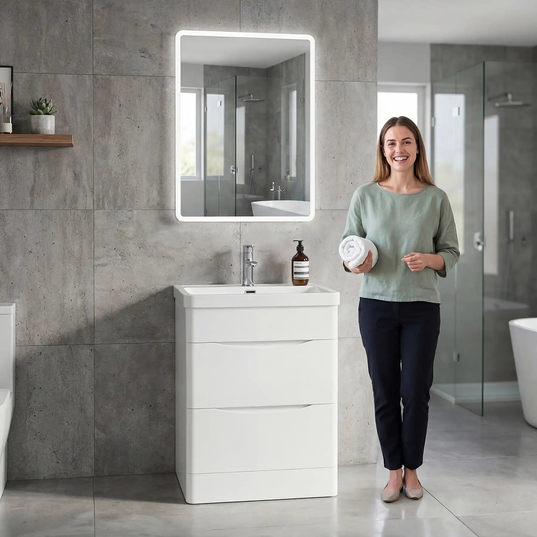 Woman standing in a modern bathroom holding a container, with a white vanity unit and illuminated mirror.