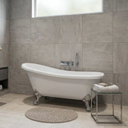 Modern bathroom with a freestanding bathtub, tiled walls, and a small table with towels.