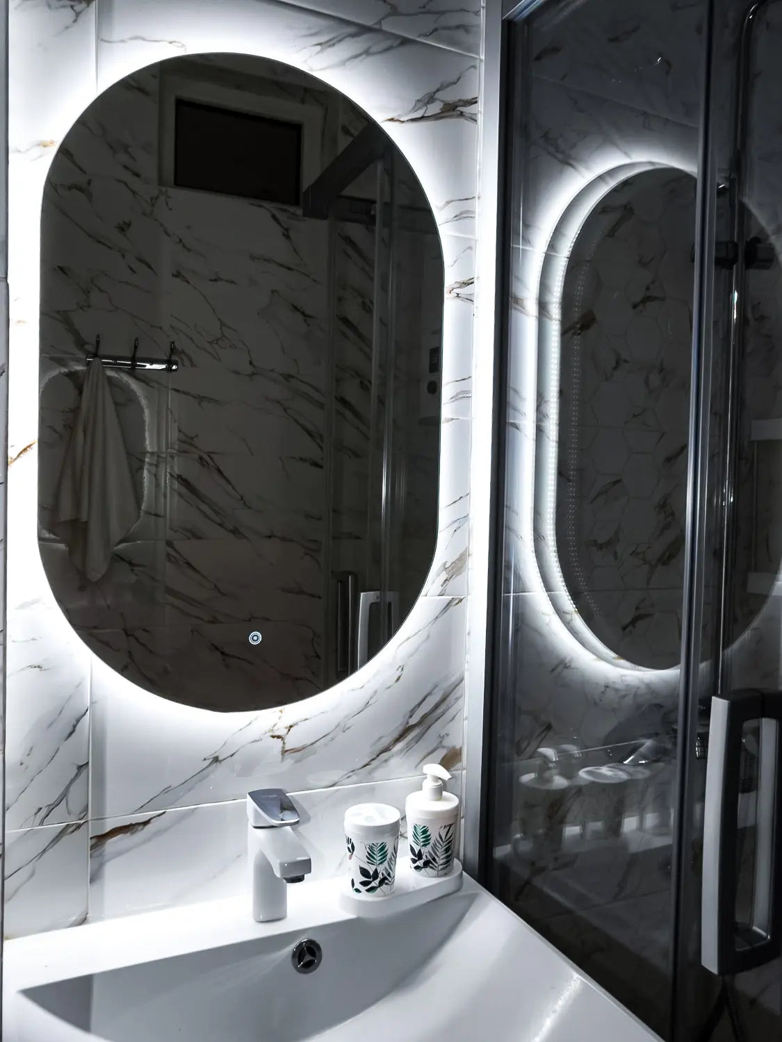 Bathroom vanity with round mirror and illuminated edges, featuring a marble-like pattern.