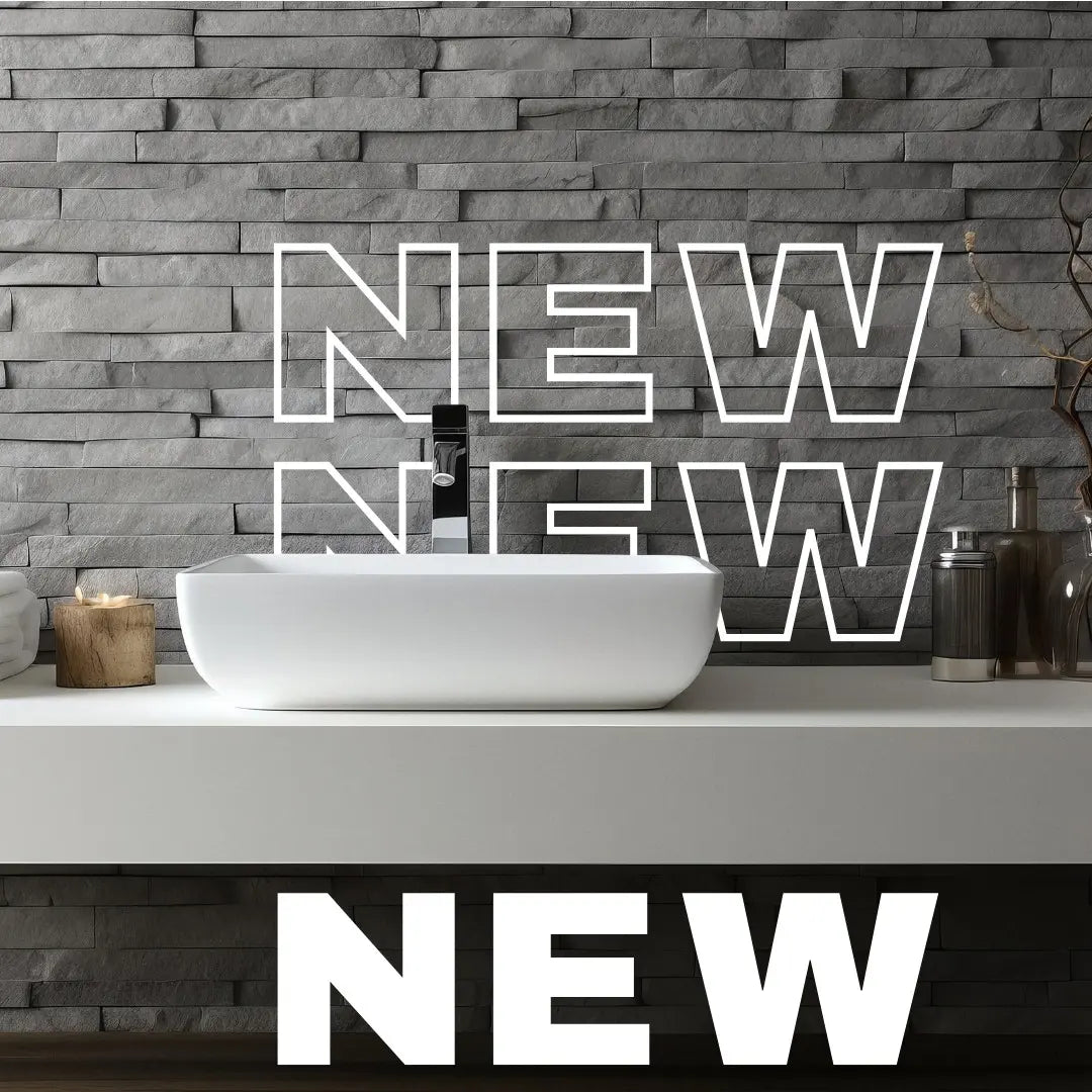 A Dreamwerks promotional banner with large white text "NEW" overlaying a bathroom setting that features a rectangular white vessel sink, a matte black faucet, and a contemporary stacked stone gray accent wall.